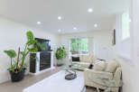 Experience modern living in this bright and airy living room, featuring a sleek fireplace and a large flat-screen TV.
