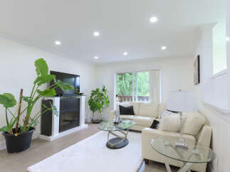 Experience modern living in this bright and airy living room, featuring a sleek fireplace and a large flat-screen TV.