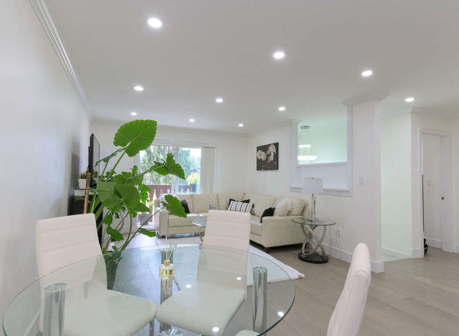 Experience modern living in this spacious open-concept home, featuring a bright living area with a plush sectional sofa and a sleek glass dining table perfect for entertaining.