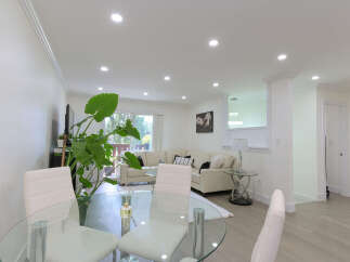 Experience modern living in this spacious open-concept home, featuring a bright living area with a plush sectional sofa and a sleek glass dining table perfect for entertaining.