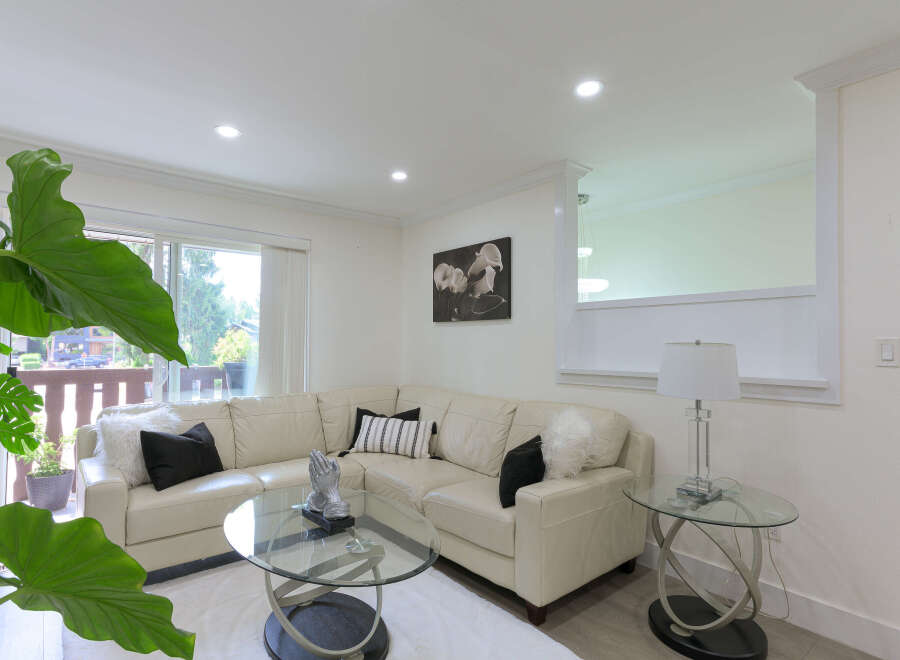 Step into this inviting living room, featuring a plush cream sectional sofa adorned with decorative pillows and a cozy white rug.