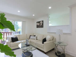 Step into this inviting living room, featuring a plush cream sectional sofa adorned with decorative pillows and a cozy white rug.