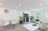This spacious living and dining area features a modern glass-top dining table with white chairs, perfect for family meals.