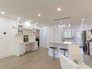 This spacious open-concept living area features a modern kitchen with a large island and sleek white cabinetry, perfect for entertaining.