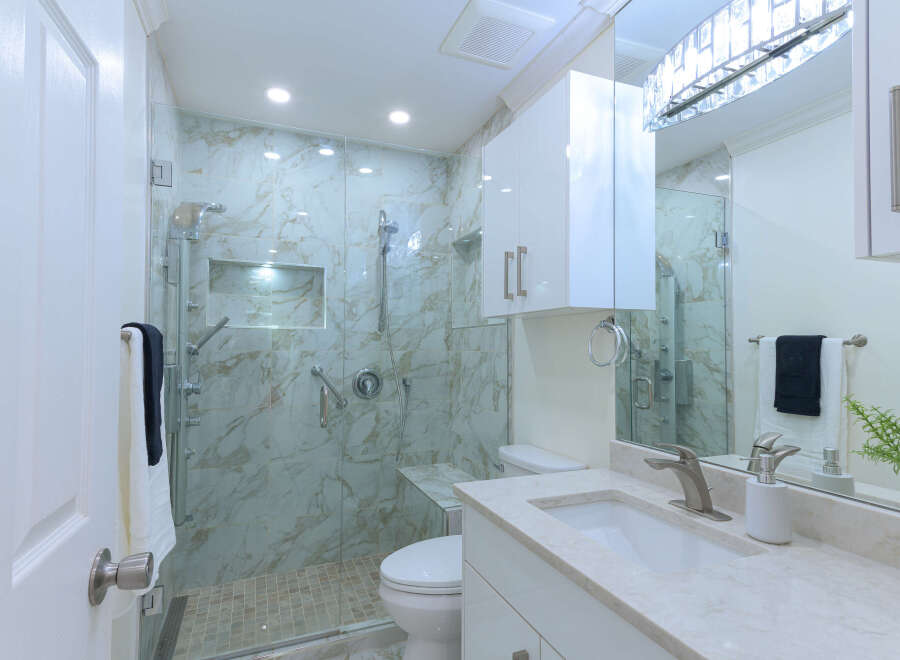 Experience modern luxury in this stunning bathroom, featuring a spacious walk-in shower with elegant marble tile and a built-in bench.