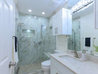 Experience modern luxury in this stunning bathroom, featuring a spacious walk-in shower with elegant marble tile and a built-in bench.