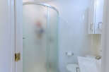 Step into this pristine white bathroom, featuring a sleek, frosted glass shower enclosure for privacy.