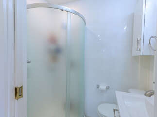 Step into this pristine white bathroom, featuring a sleek, frosted glass shower enclosure for privacy.