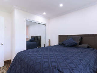 This bedroom features a spacious bed with a dark blue comforter and matching pillows, complemented by a dark wood headboard.