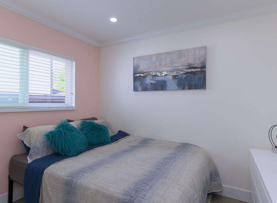 This inviting bedroom features a comfortable bed adorned with plush teal throw pillows and a stylish abstract duvet.