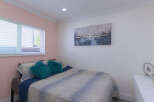 This inviting bedroom features a comfortable bed adorned with plush teal throw pillows and a stylish abstract duvet.