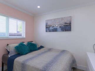 This inviting bedroom features a comfortable bed adorned with plush teal throw pillows and a stylish abstract duvet.
