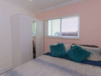 Discover this charming bedroom featuring a spacious white wardrobe with mirrored doors, perfect for ample storage.