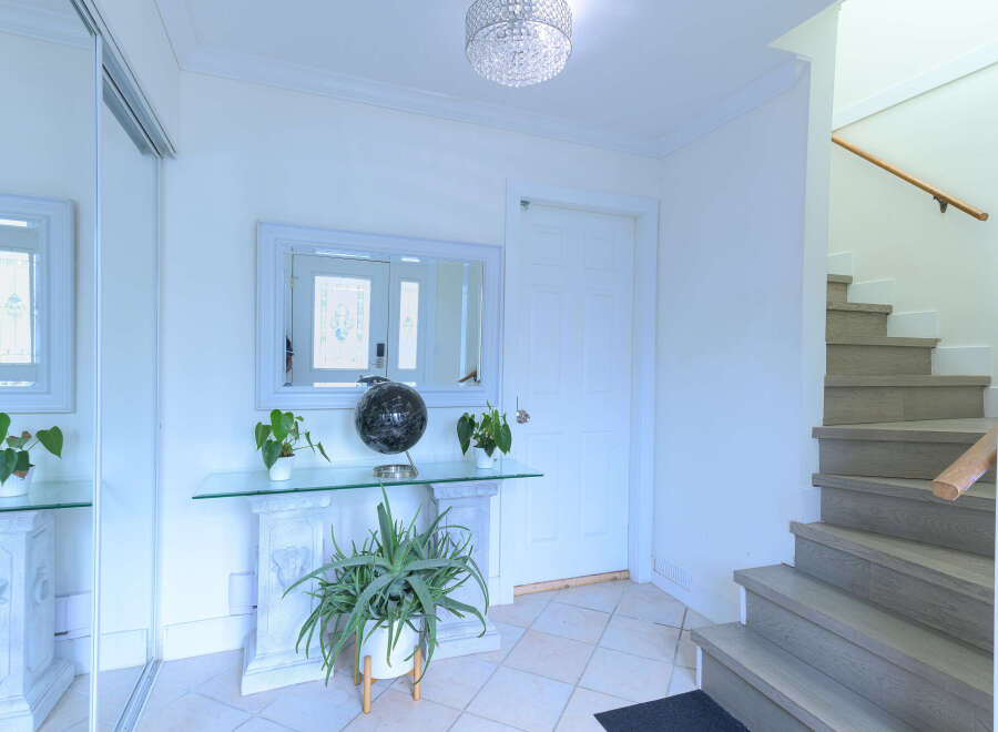 Step into a bright and airy entryway featuring a sleek mirrored closet and a stylish console table adorned with plants and a decorative globe.