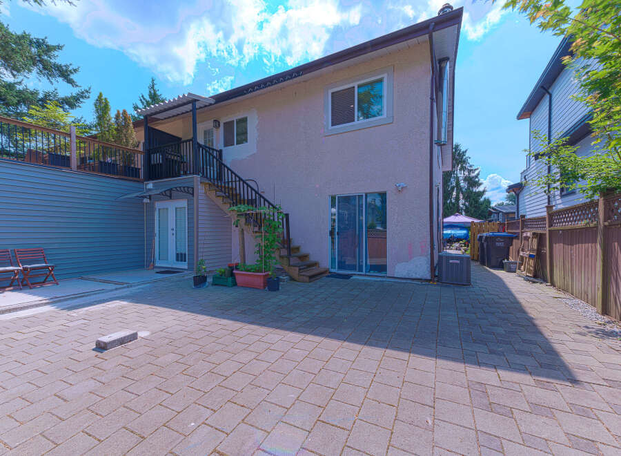 Enjoy outdoor living in this spacious backyard featuring a paved patio perfect for entertaining and a raised deck with seating.
