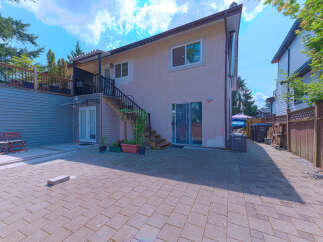 Enjoy outdoor living in this spacious backyard featuring a paved patio perfect for entertaining and a raised deck with seating.