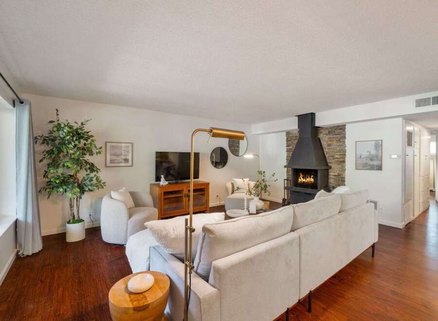 Experience cozy living in this inviting living room, featuring a striking stone fireplace with a modern black hearth as the centerpiece.