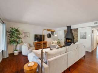 Experience cozy living in this inviting living room, featuring a striking stone fireplace with a modern black hearth as the centerpiece.