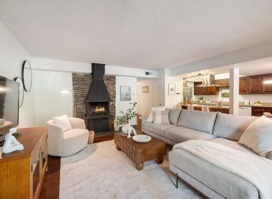 Experience modern living in this stunning open-concept living space, featuring a cozy fireplace with a stone accent wall and a sleek, contemporary design.