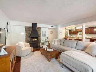 Experience modern living in this stunning open-concept living space, featuring a cozy fireplace with a stone accent wall and a sleek, contemporary design.