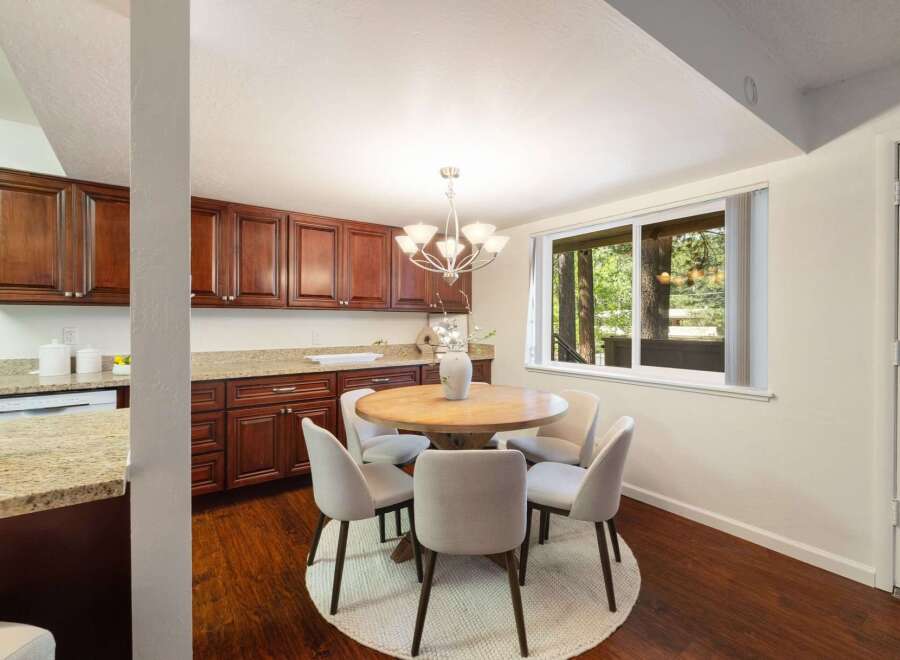 Enjoy meals with a view in this charming dining area, featuring a round wooden table surrounded by comfortable upholstered chairs.