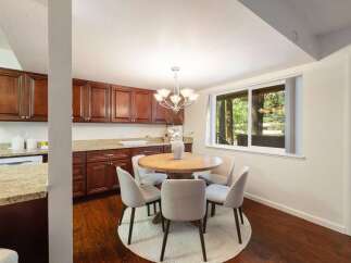 Enjoy meals with a view in this charming dining area, featuring a round wooden table surrounded by comfortable upholstered chairs.