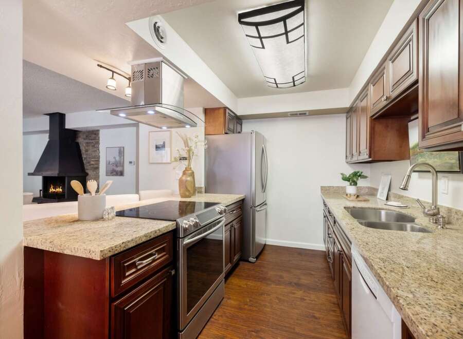 Experience modern living in this stunning kitchen, featuring a sleek stainless steel range and hood, complemented by rich cherry wood cabinetry.