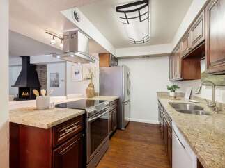 Experience modern living in this stunning kitchen, featuring a sleek stainless steel range and hood, complemented by rich cherry wood cabinetry.