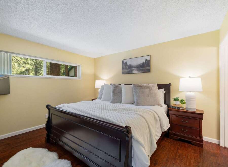 Experience serene living in this charming bedroom, featuring a cozy queen-size bed adorned with plush pillows and a soft white comforter.