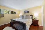 Experience serene living in this charming bedroom, featuring a cozy queen-size bed adorned with plush pillows and a soft white comforter.
