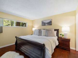 Experience serene living in this charming bedroom, featuring a cozy queen-size bed adorned with plush pillows and a soft white comforter.