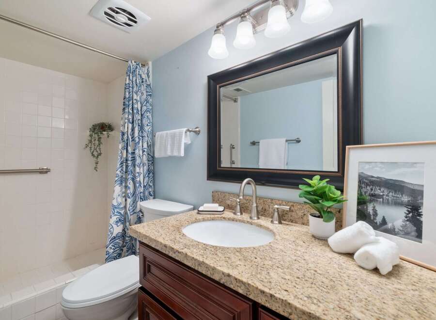 This charming bathroom features a spacious vanity with a granite countertop and dark wood cabinetry, offering ample storage.
