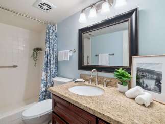 This charming bathroom features a spacious vanity with a granite countertop and dark wood cabinetry, offering ample storage.