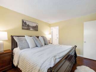 Experience ultimate comfort in this beautifully appointed bedroom, featuring a plush king-size bed adorned with soft, inviting pillows and a luxurious white duvet.