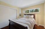 This cozy bedroom features a dark wood sleigh bed adorned with crisp white linens and a textured throw blanket.