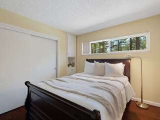 This cozy bedroom features a dark wood sleigh bed adorned with crisp white linens and a textured throw blanket.