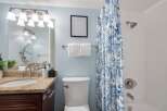 This bright and airy bathroom features a spacious vanity with a granite countertop and ample storage.