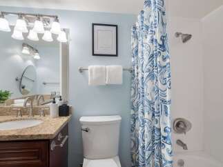 This bright and airy bathroom features a spacious vanity with a granite countertop and ample storage.