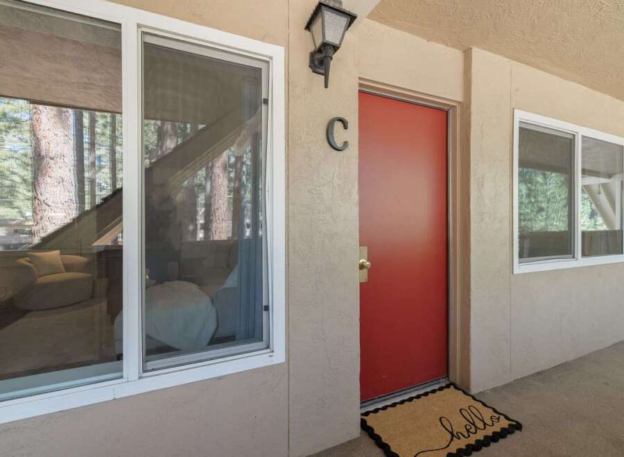 Welcome guests to this charming property with a vibrant red door and a welcoming 'hello' doormat.