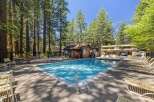 Enjoy a refreshing dip in the sparkling blue swimming pool, surrounded by tall pine trees and ample lounge chairs for relaxation.