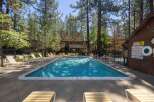 Enjoy a refreshing dip in this beautiful swimming pool, surrounded by lush pine trees and comfortable lounge chairs perfect for soaking up the sun.