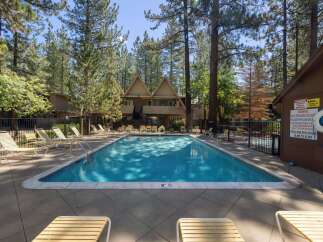 Enjoy a refreshing dip in this beautiful swimming pool, surrounded by lush pine trees and comfortable lounge chairs perfect for soaking up the sun.