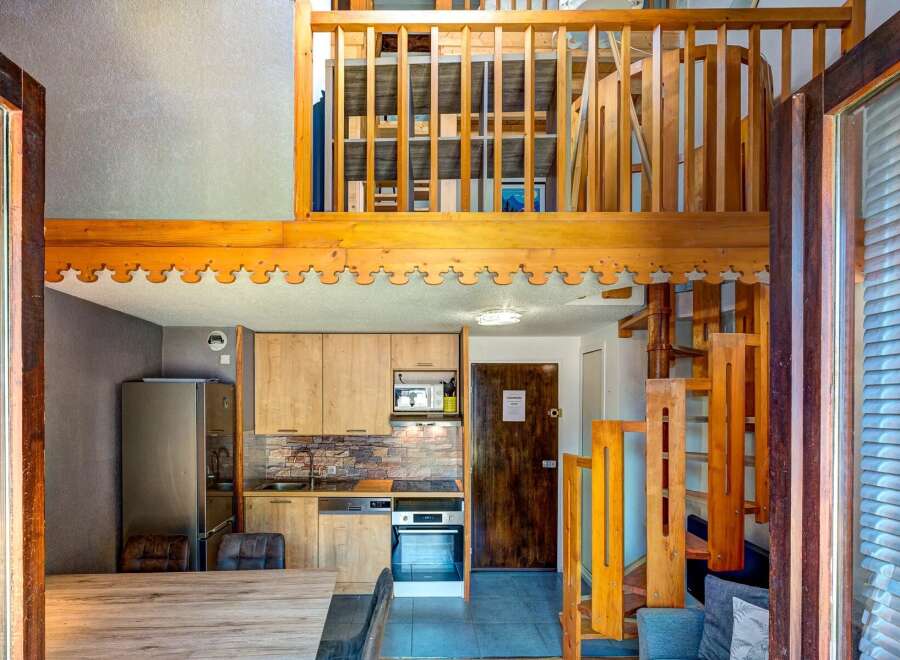 Discover this charming loft apartment featuring a modern kitchen with light wood cabinetry and stone backsplash, perfect for preparing meals.