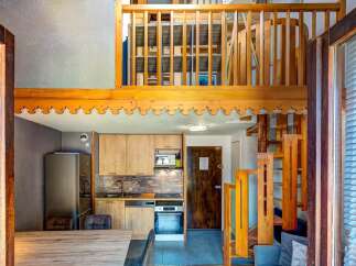 Discover this charming loft apartment featuring a modern kitchen with light wood cabinetry and stone backsplash, perfect for preparing meals.