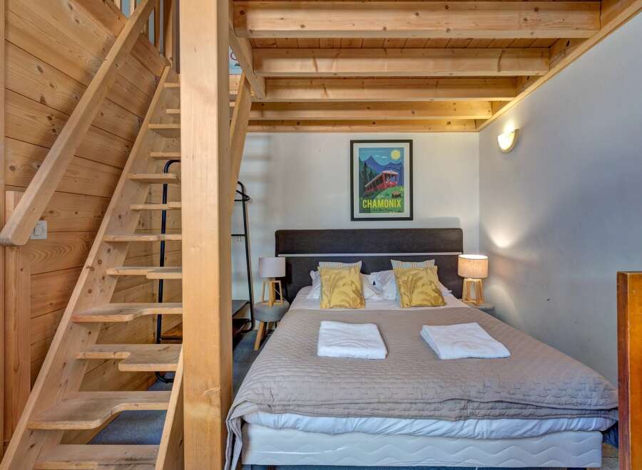 Experience cozy mountain living in this charming bedroom featuring a comfortable bed adorned with plush pillows and crisp white towels.