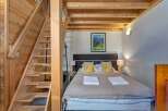 Experience cozy mountain living in this charming bedroom featuring a comfortable bed adorned with plush pillows and crisp white towels.