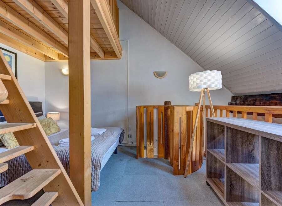 Discover this charming loft bedroom featuring a unique wooden bunk bed structure with a convenient ladder for access.