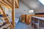 Discover this charming loft bedroom featuring a unique wooden bunk bed structure with a convenient ladder for access.