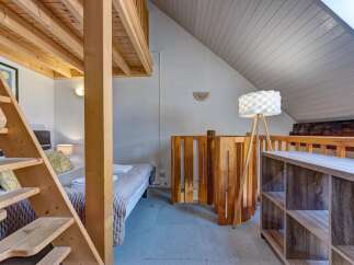 Discover this charming loft bedroom featuring a unique wooden bunk bed structure with a convenient ladder for access.