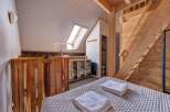 Experience cozy living in this charming loft bedroom, featuring a comfortable bed adorned with fresh white towels.